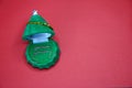 Green box in the form of a Christmas tree with earrings inside on a red background