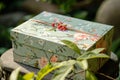 A green box with a red bow on top, showcasing delicate floral patterns for a sophisticated gift presentation, An elegant gift box Royalty Free Stock Photo