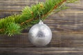 Green branch of a Christmas tree with a silver ball on a wooden table Royalty Free Stock Photo