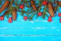 green branches of needles and yellow Christmas garland, red decorations on a blue wooden background Royalty Free Stock Photo