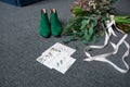 Green bridal shoes, rich green wedding bouquet with pink ribbons and a wedding complimentary lying on a grey floor Royalty Free Stock Photo