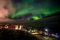 Green bright northern lights hidden by the clouds over the Inuit village at the fjord, Nuuk city, Greenland
