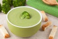 Green broccoli cream soup in a bowl with wooden