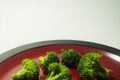 Green Brocolli on Red and Black Plate on White Background Royalty Free Stock Photo