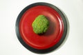 Green Brocolli on Red and Black Plate on White Background Royalty Free Stock Photo