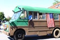 A green and brown school bus driving through the fourth of July parade