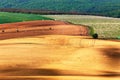 Green and brown spring ploughland. Rolling arable fields