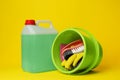 Green bucket, cleaning supplies and tools on yellow background Royalty Free Stock Photo