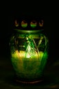Green burning votive candle in the dark Royalty Free Stock Photo