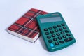 Green calculator lying near red plaid notebook on white background Royalty Free Stock Photo