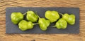 Green cambuci peppers on a stone board over wooden table. Typical brazilian ingredient