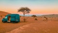 Green camper van is parked on a dirt road in a vast desert landscape.