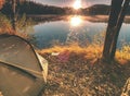 Green camping tent at lake in early morning