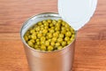 Green canned peas in open iron bank is on the table.