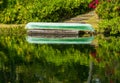 Green canoe on dock reflecting into calm lake or pond in garden Royalty Free Stock Photo