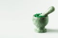 Green capsules and orange pills with mortar pestles on white background. Royalty Free Stock Photo