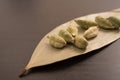 Green cardamom in dried Indian bay leaves on a black background