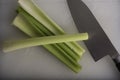 Green Celery Being Sliced on White Cutting Board