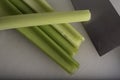 Green Celery Being Sliced on White Cutting Board