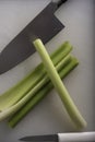 Green Celery Being Sliced on White Cutting Board