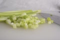 Green Celery Being Sliced on White Cutting Board
