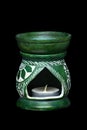 Green ceramic aroma lamp with candles on a black background