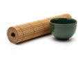 A green ceramic bowl sits next to a rolled bamboo sushi mat on a Royalty Free Stock Photo
