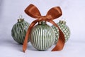 Green ceramic Christmas baubles with red ribbon bow on light background. Royalty Free Stock Photo