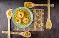 Green ceramic plate and bamboo spatulas with different paste on a bamboo napkin and a wooden background