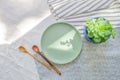 Green ceramic plate on cotton tablecloth with decorative wooden spoons and Echeveria plant. Healthy food and organic products