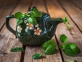 Green ceramic teapot with fresh mint on a wooden table