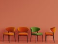 A green chair among orange chairs on orange pastel backgrond