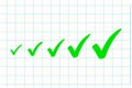 Green check marks in increasing size on squared paper. Royalty Free Stock Photo