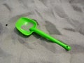 Green children`s shovel on the beach. Ready to playin the fine sands.