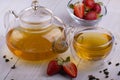 Green oolong tea with strawberrie in a glass clear cup and glass teapot, brown sugar, close-up, selective focus on the Royalty Free Stock Photo