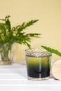 Green Chlorophyll drink in glass with water drops on white table, Orange Background. Antioxidant food and drinks Royalty Free Stock Photo