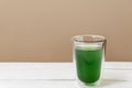 Green chlorophyll drink in a glass on white table