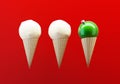 Green christmas ball in ice cream waffle cone and snowballs on red background