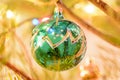 Green Christmas balloon on a Christmas tree against the background of shining garlands. Green ball surrounded by branches of the C Royalty Free Stock Photo