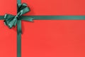 Green Christmas gift ribbon bow on plain red background paper, copy space Royalty Free Stock Photo