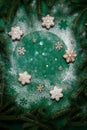 Green Christmas and New Year festive green background with snowflake shape gingerbread, fir tree branches and snow Royalty Free Stock Photo