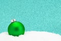 A Green Christmas Ornament in the Snow with a Glittery Background Royalty Free Stock Photo