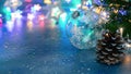 Green christmas tree branch, pine cone and glass ball on background of blurred glowing christmas lights Royalty Free Stock Photo