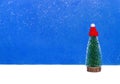 Green christmas tree in red cap under the snow on light blue background Royalty Free Stock Photo