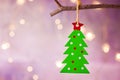 Green Christmas tree with red star ornament hanging on branch. Shining garland golden lights. Purple background. Royalty Free Stock Photo