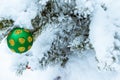 Green Christmas tree toy on a snow-covered spruce branch. Close-up Royalty Free Stock Photo