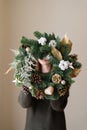 Green Christmas wreath on female hands. Woman florist holding xmas decorative wreath on white wall background. Seasonal Royalty Free Stock Photo