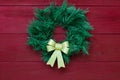 Green Christmas wreath with gold bow hanging on antique red wooden door