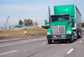 Green big rig semi truck with covered rubber semi trailer running on the highway Royalty Free Stock Photo