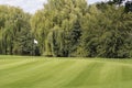 Green clean golf field with one white flag